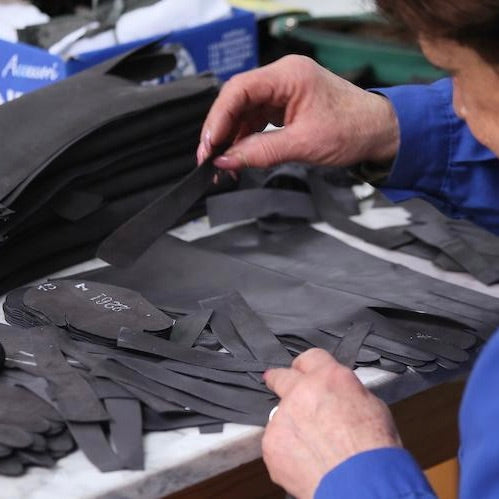 Woman working in a glove factory with pieces of leather.