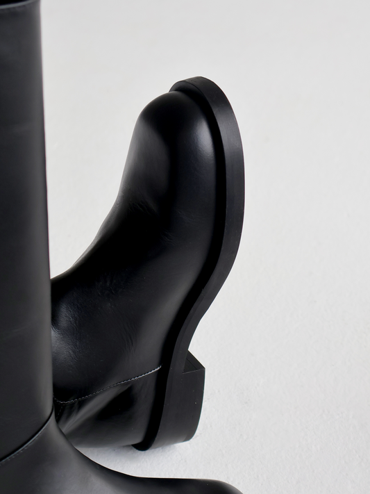 Black leather boots on a light gray background