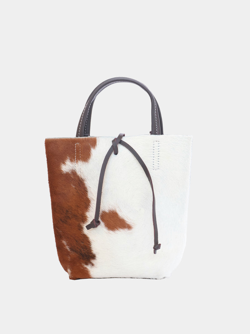 Carpi mini tote bag with cow-print pony hair and brown leather straps, front view.