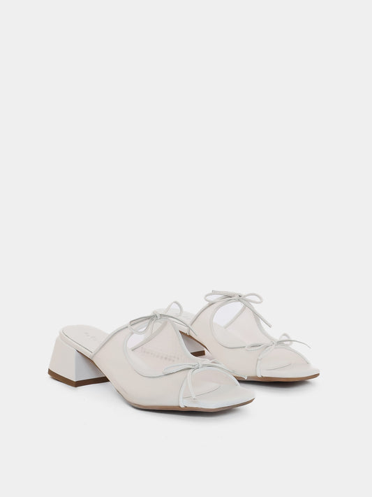 Pair of white shoes with a block heel on a light gray background