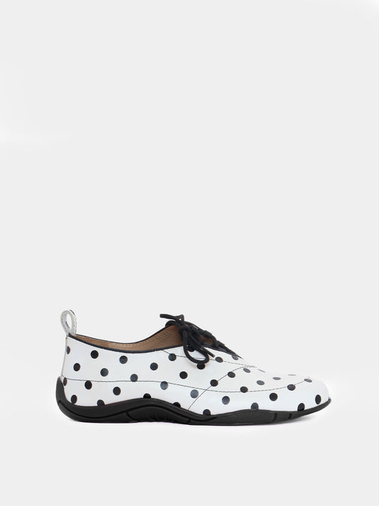 white and black polka dot asymmetrical sneaker on gray background