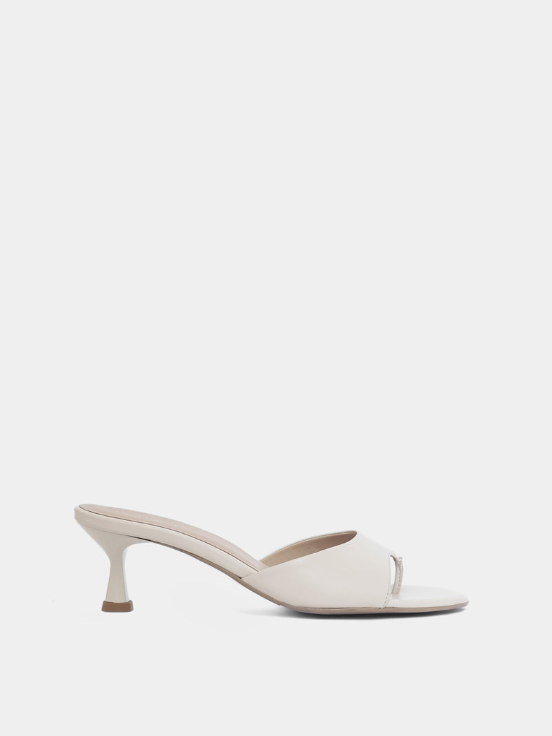 Side view of cream colored open toe heeled sandal on white background