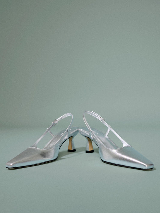 A pair of silver heel on a light blue background