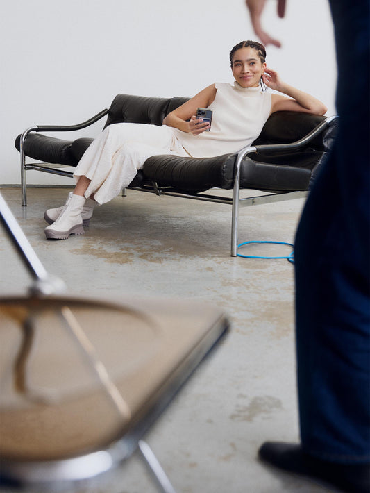 Model dressed all black with Estrella boots White and Taupe. She's sitting on a couch
