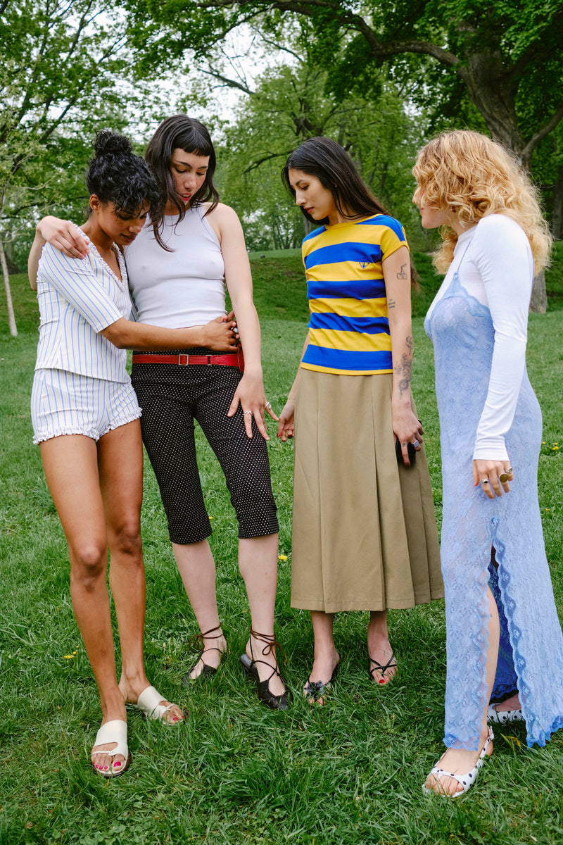 Four women standing on grass with trees in the background