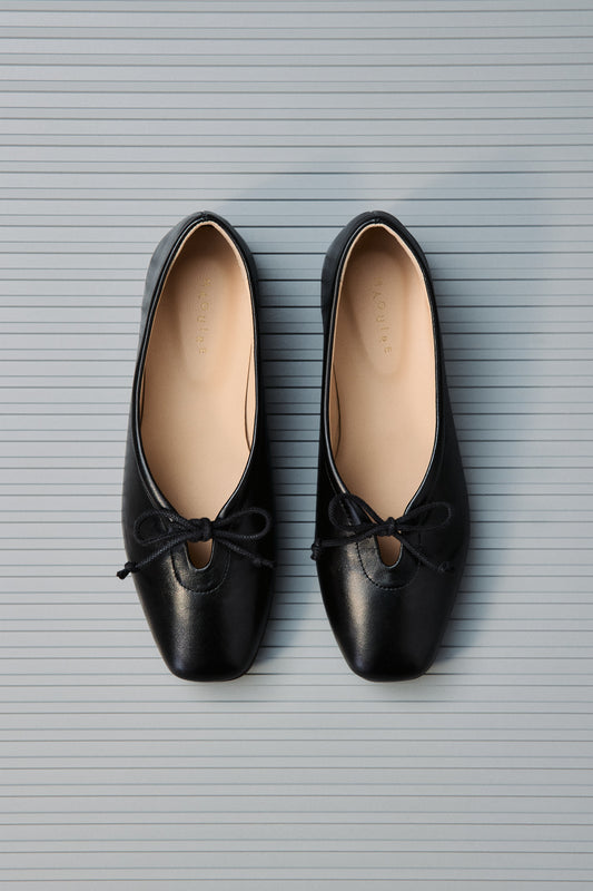 Pair of black shoes with bows on a textured gray background