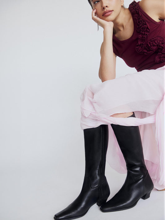 Model with a pink skirt, bordeaux top and high black boots