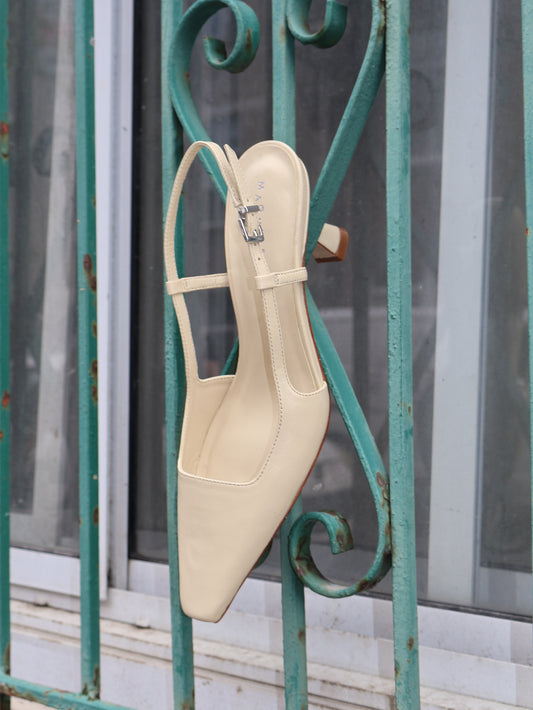Beige high-heeled shoe on a green metal railing.