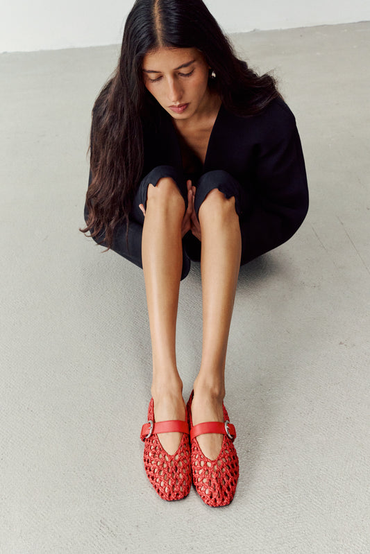 Woman wearing woven red shoes while sitting down