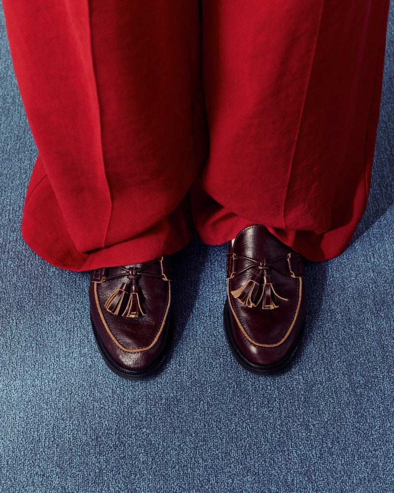 woman wearing bright red pants and brown loafers standing on blue carpet