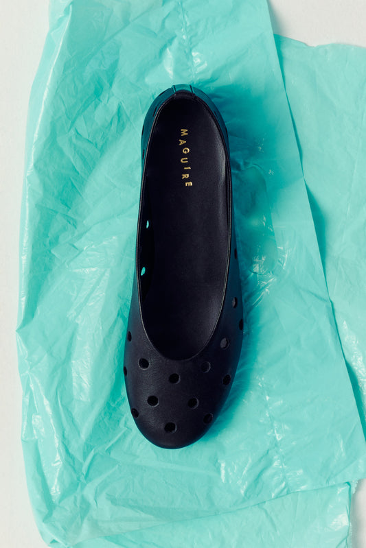 black ballet flat with round cutouts on turquoise paper bag