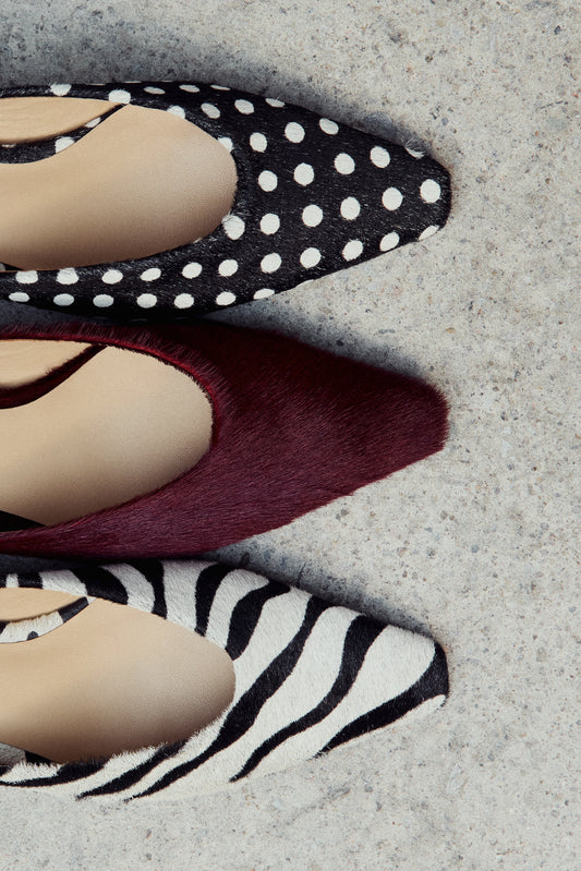 Three pairs of shoes with zebra pattern, burgundy, and polka dot design on a textured surface.