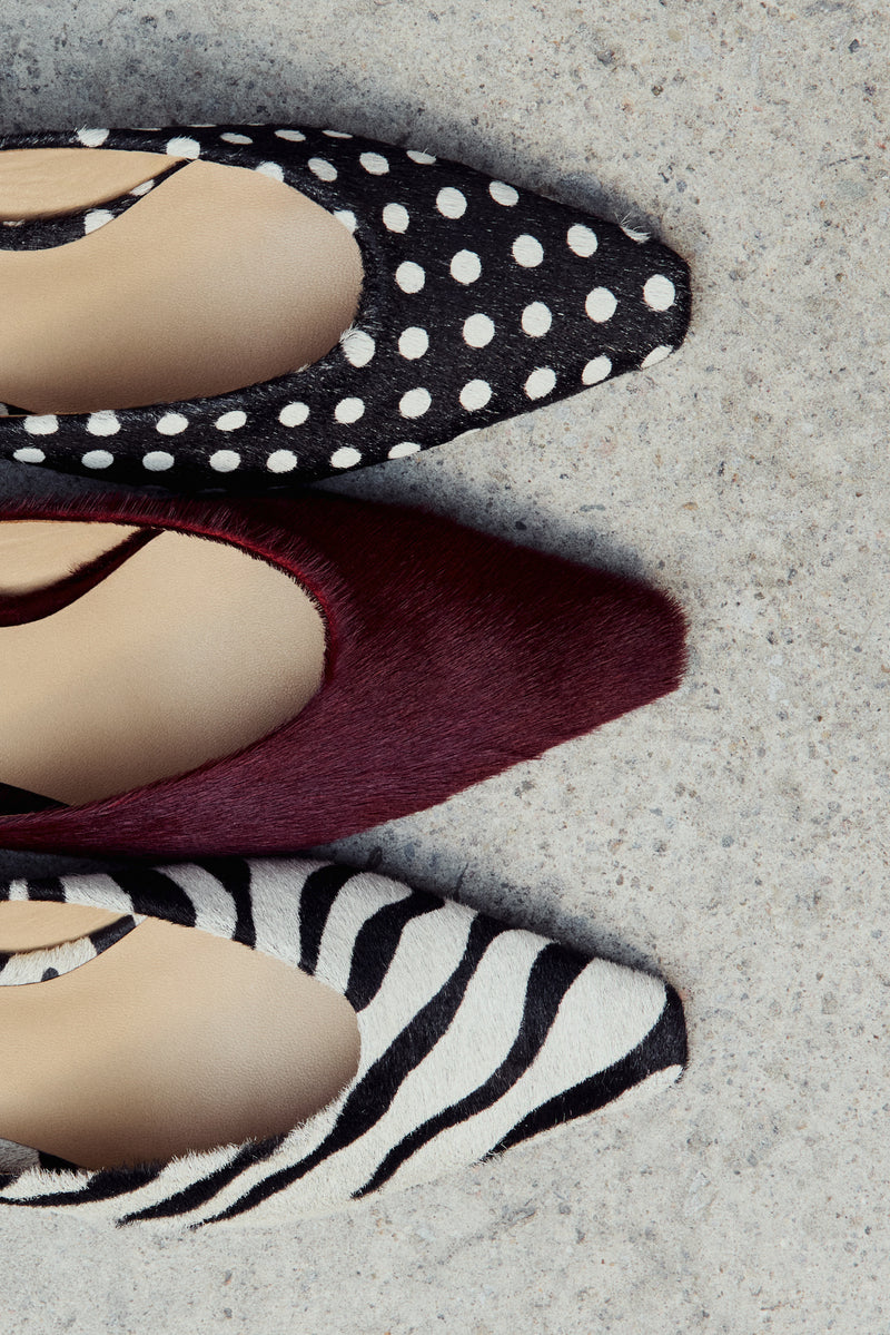 Three pairs of shoes with zebra pattern, burgundy, and polka dot design on a textured surface.