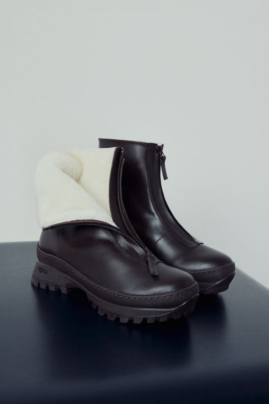 Pair of black boots with white lining on a dark surface and light gray background