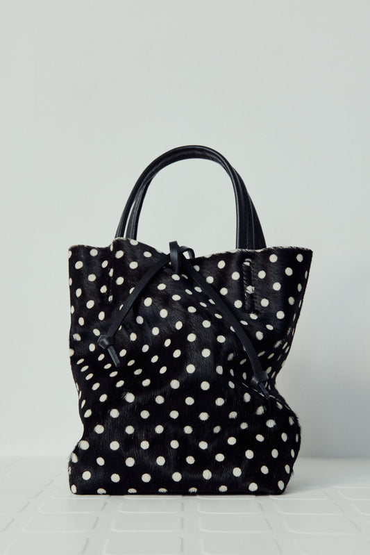 Black tote bag with white polka dots on a light gray background