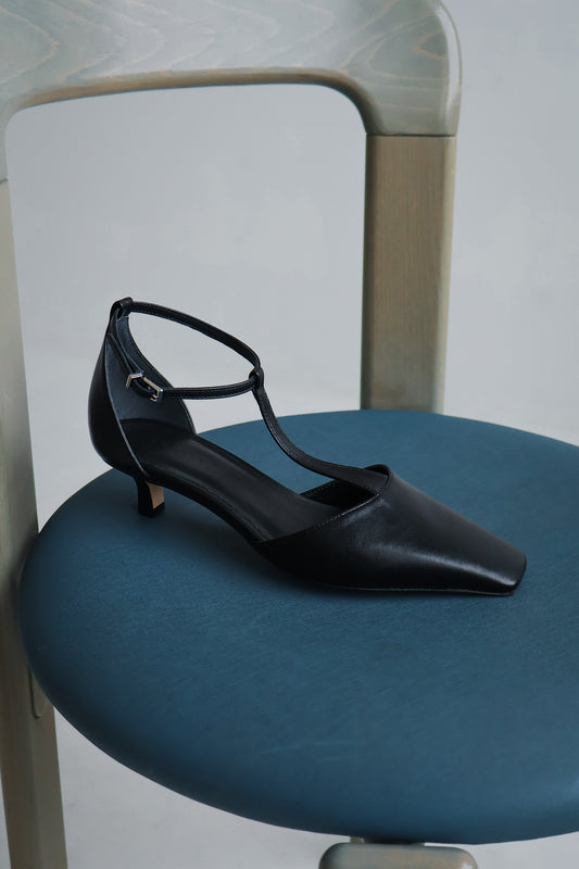 Black high-heeled shoe on a blue chair with a neutral background