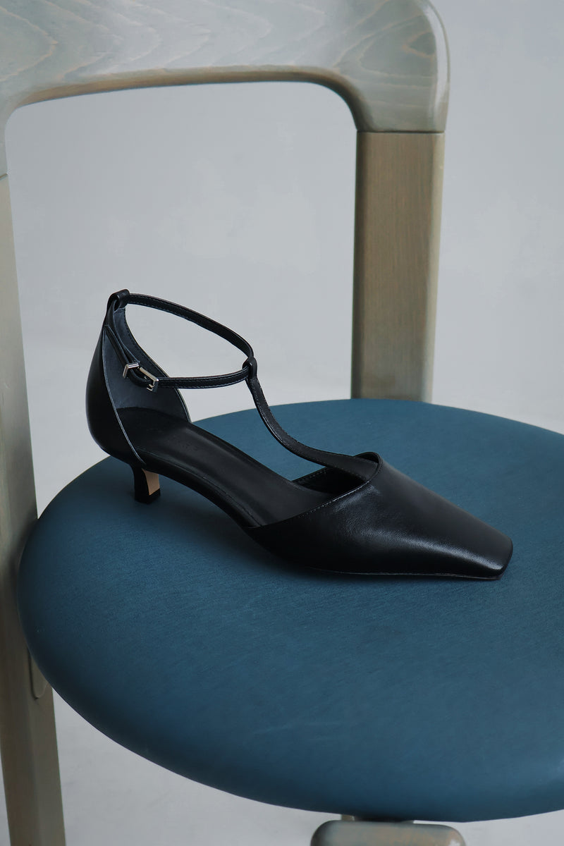Black high-heeled shoe on a blue chair with a neutral background
