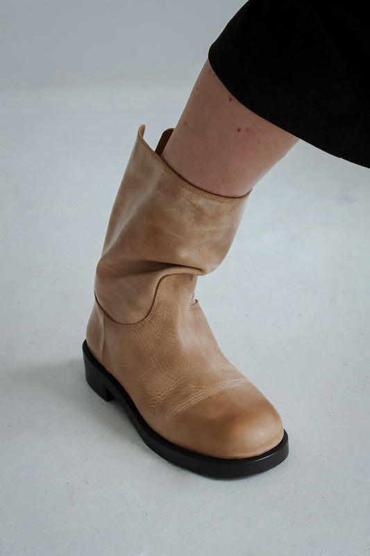 Tan leather boot on a light gray background