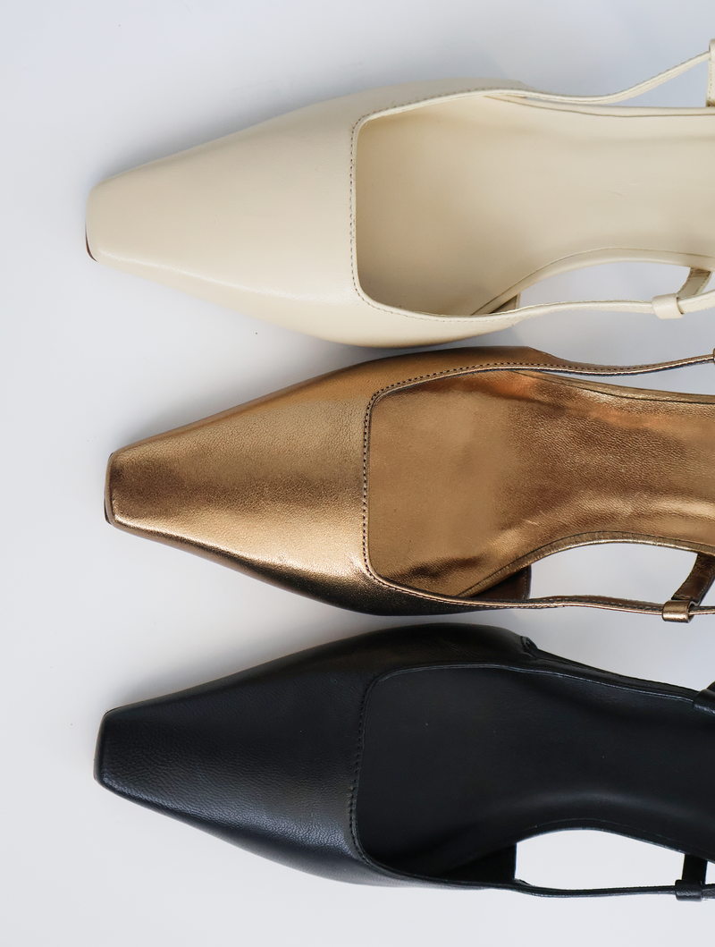 Three pairs of high-heeled shoes in beige, bronze, and black on a light gray background.