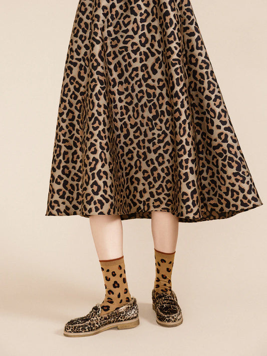 A person wearing animal print espadrilles,skirt and matching cheetah print socks.