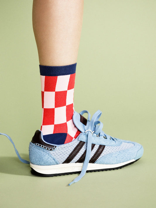 Close up on an Adidas sneaker with red checkered red, navy and white socks